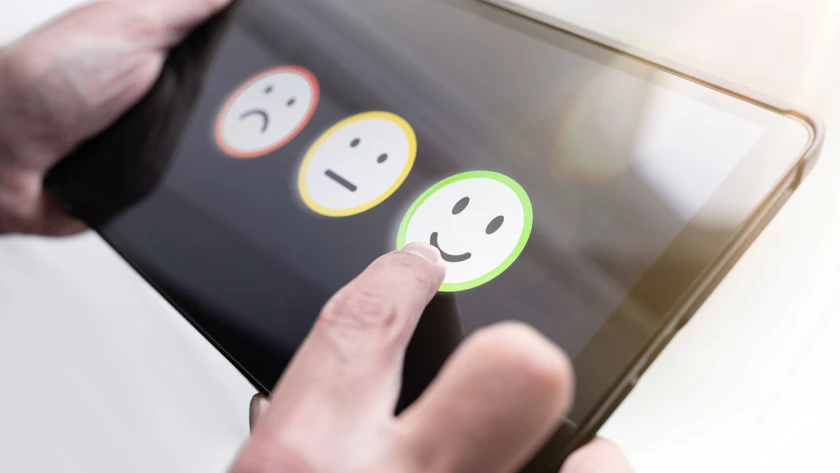 pleased person giving positive feedback by touching smiley face on digital tablet touchscreen