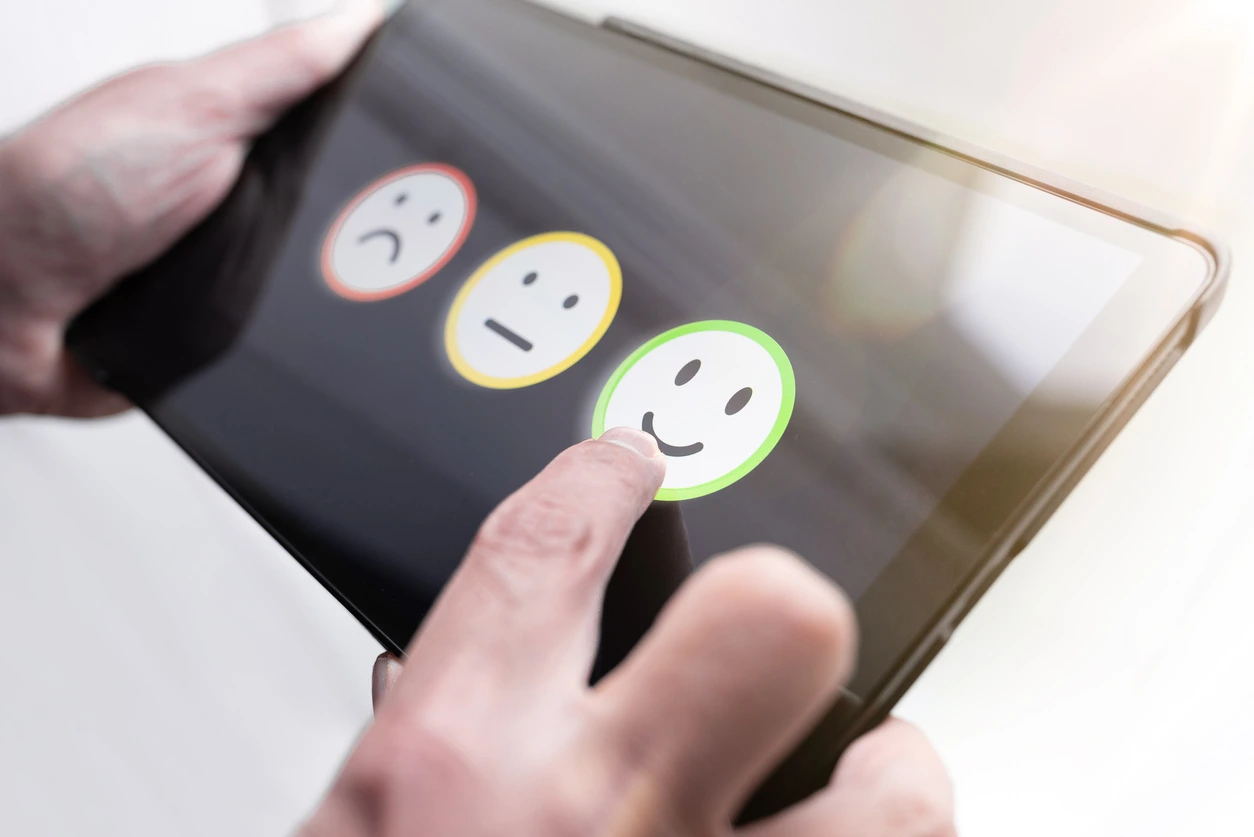 pleased person giving positive feedback by touching smiley face on digital tablet touchscreen