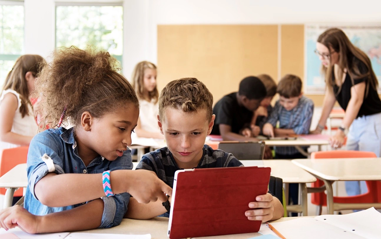 Zwei Kinder arbeiten gemeinsam an einem Tabelt in der Schule